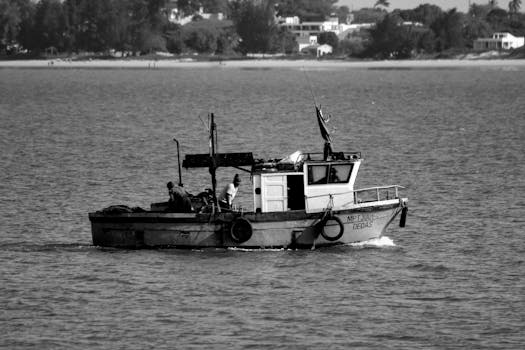 在靠近海岸的宁静大海上，一艘渔船和船员构成了一幅黑白照片