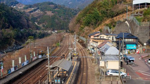 Free Scenic view of a rural Japanese train station surrounded by mountains. Stock Photo