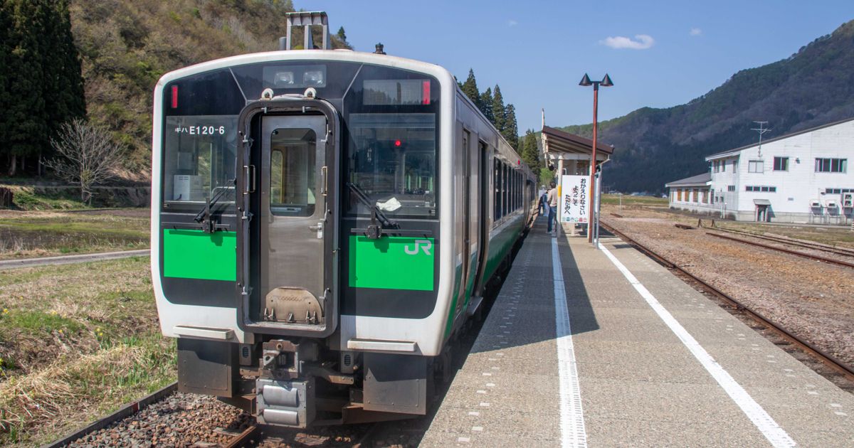 山あいの駅に停まる緑の帯の気動車