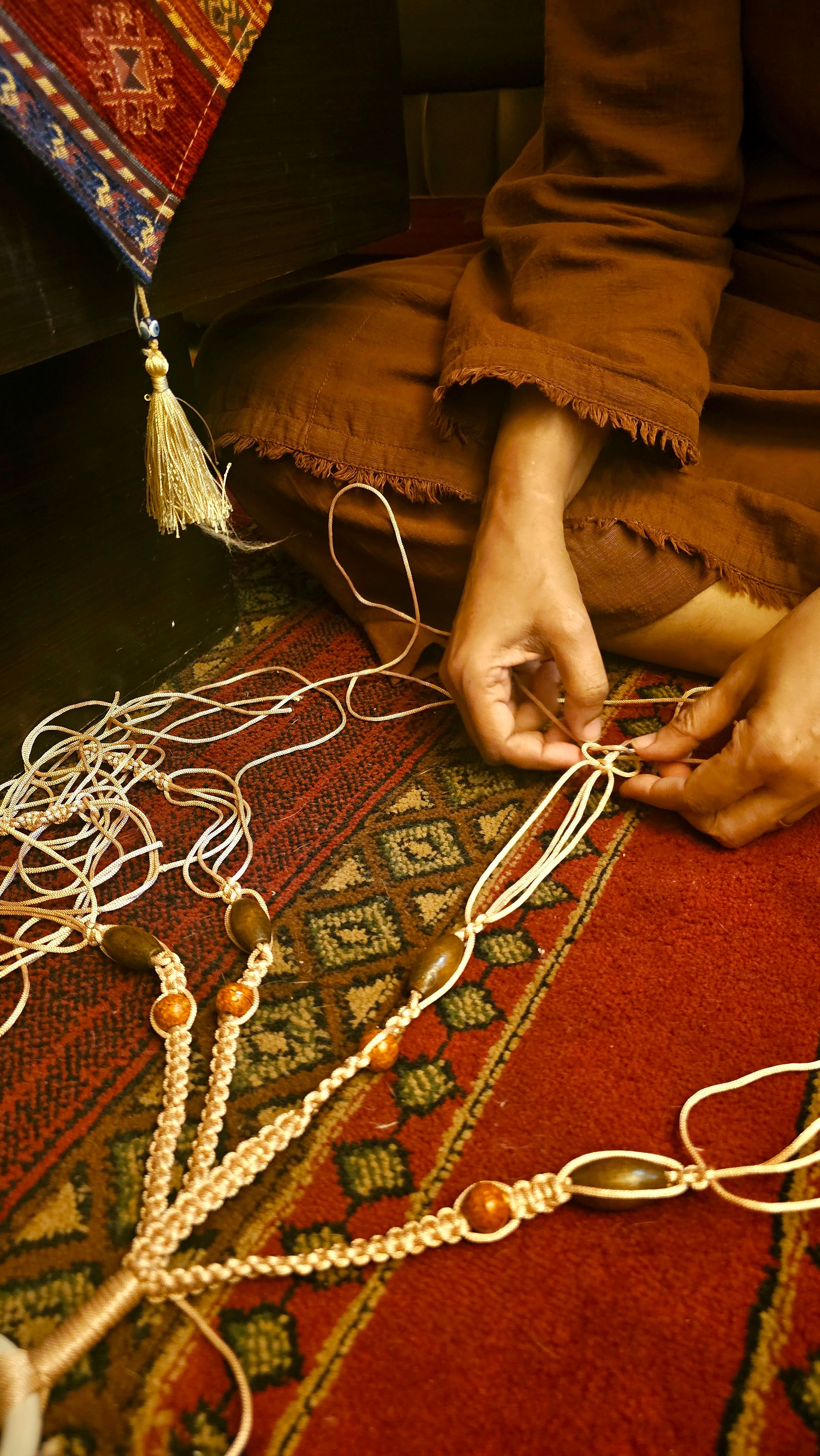 Close-up of hands weaving macramé art on a detailed rug showcasing intricate craftsmanship.