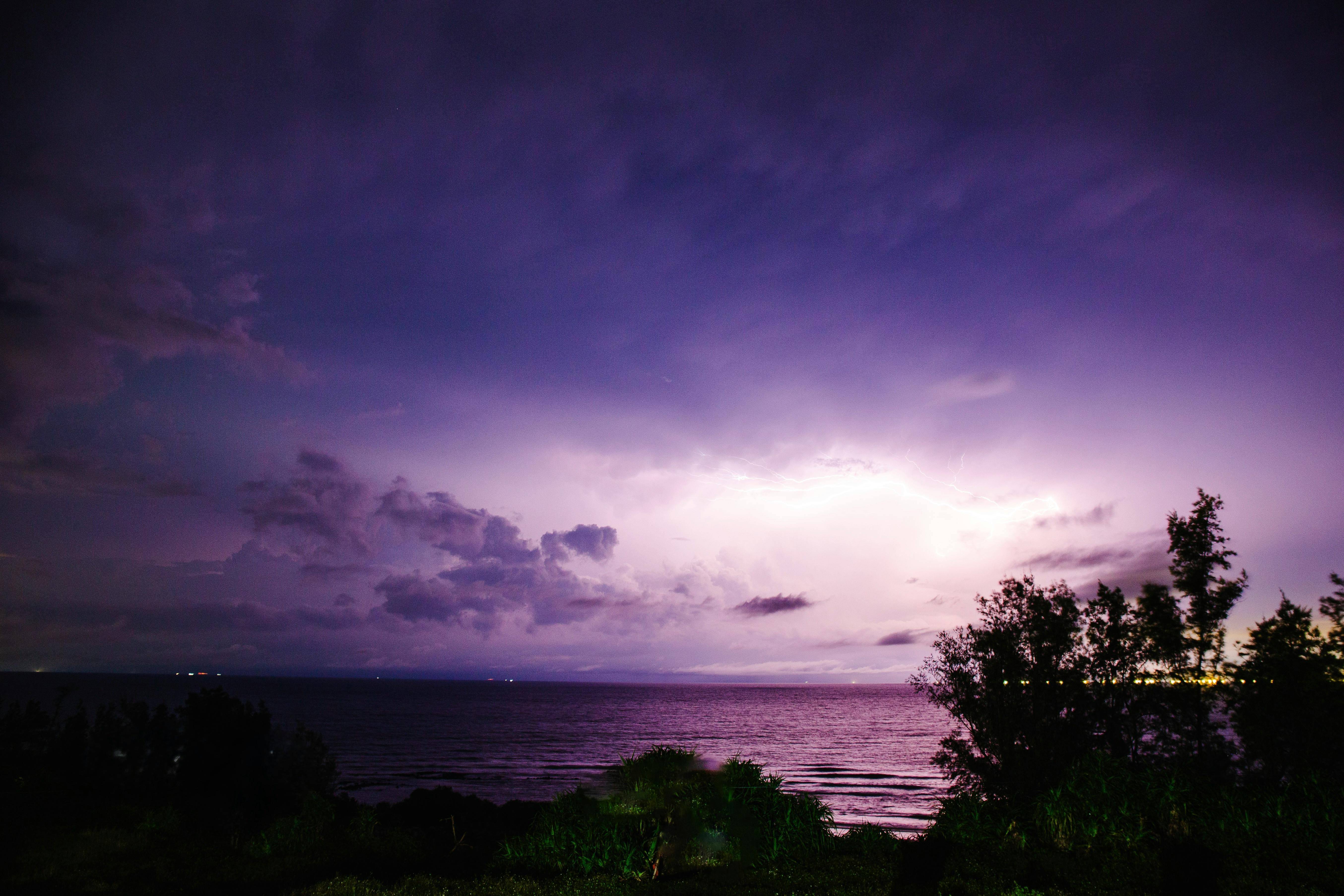 迷人的紫色雷暴在夜间海洋上空绽放