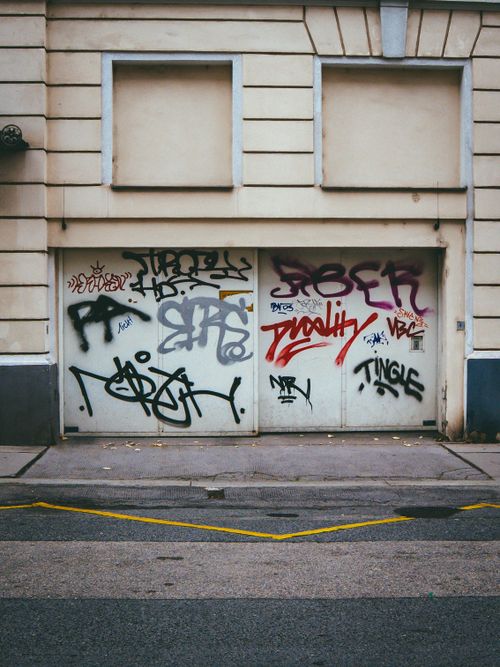 Free Colorful graffiti art adorns a garage door in an urban alley, showcasing street culture. Stock Photo