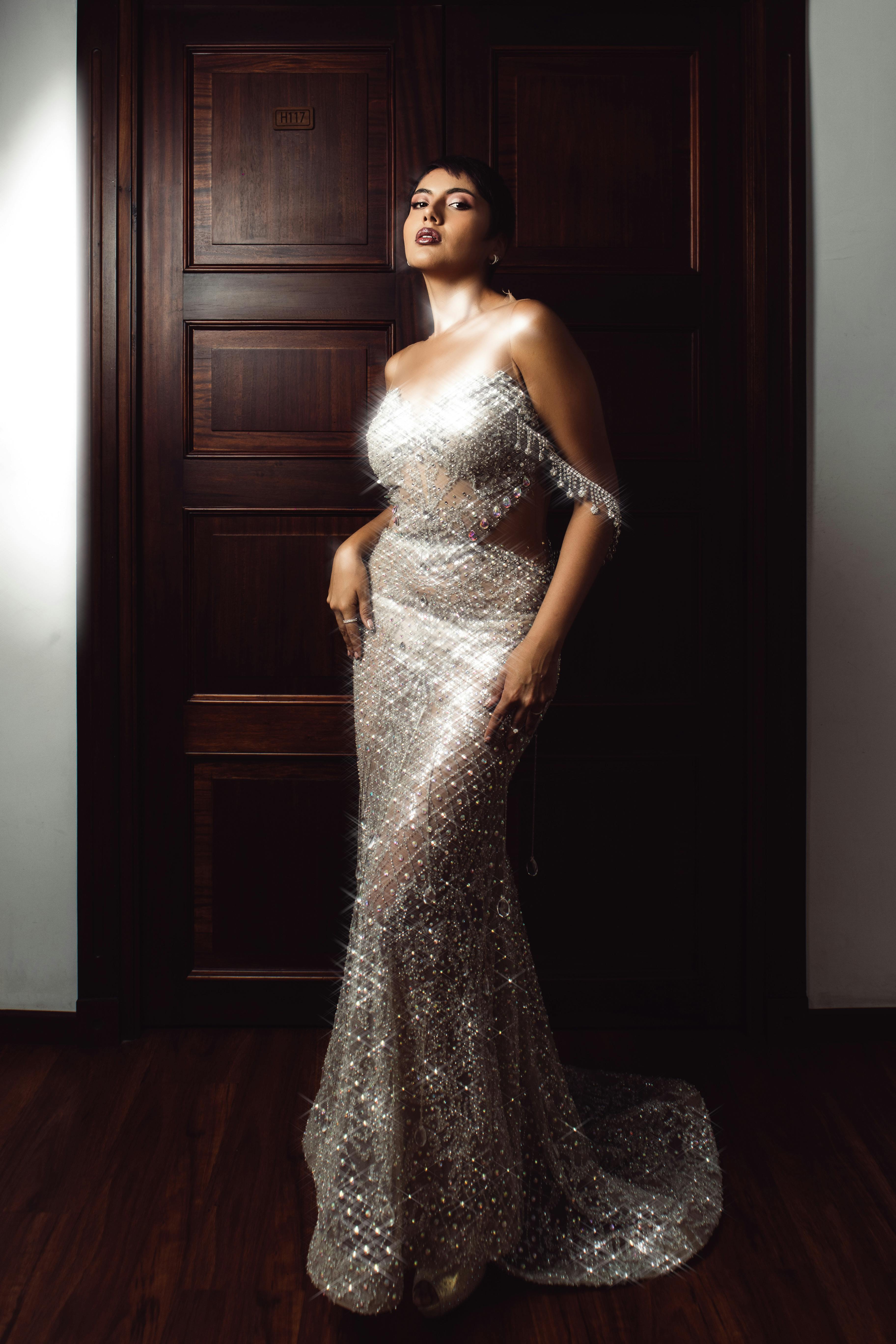 一位穿着耀眼闪亮礼服的女性在室内自信地摆姿势的时尚肖像