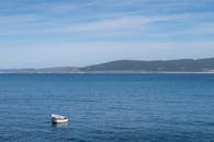 一艘白色的船漂浮在晴朗的天空下，宁静的蓝色海水上