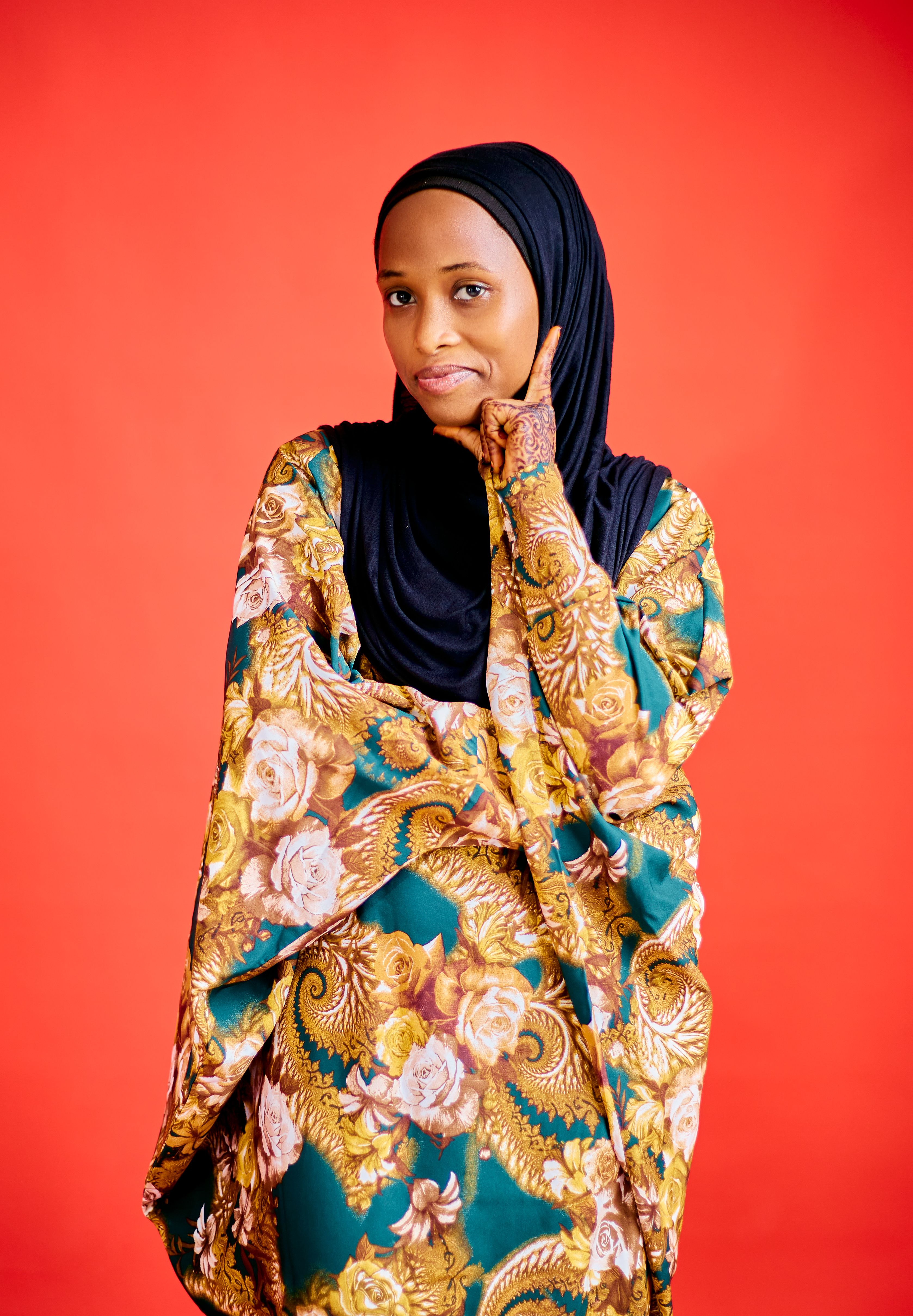 Portrait of a woman in vibrant traditional attire against a red background.