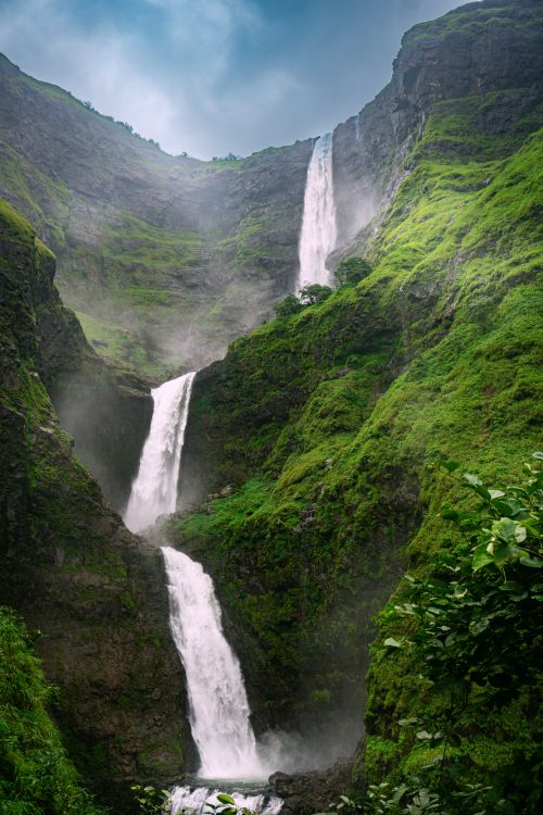 Free Stunning view of a towering three-tier waterfall nestled in a lush green valley during daytime. Stock Photo