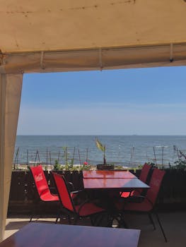 在海滨咖啡馆，令人放松的景观中，红色椅子与平静的海洋背景相映成趣