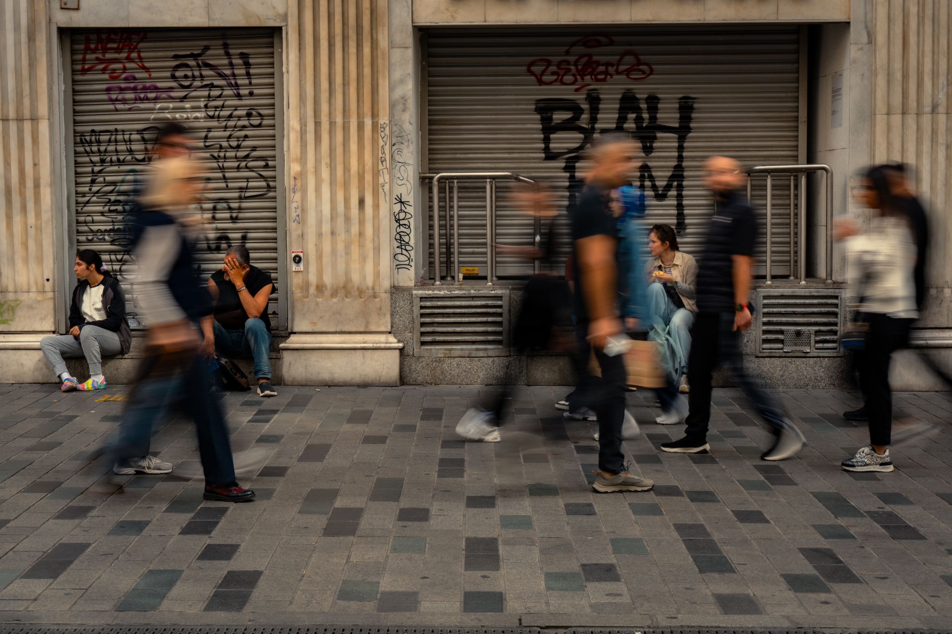 Street scene with people in motion blur, depicting urban life and public space dynamics.