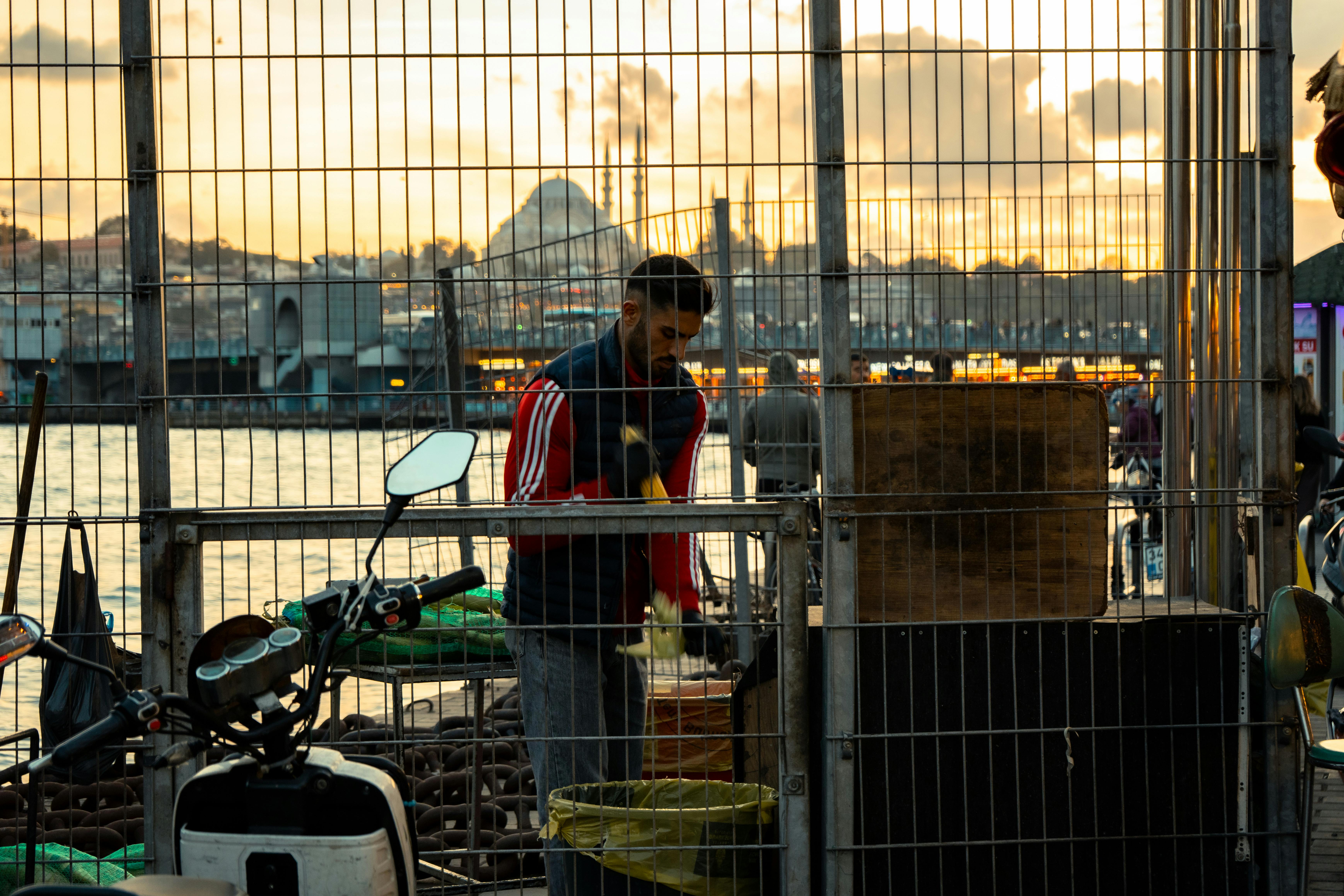 在城市和日落的背景下，一个供应商正在河边附近工作