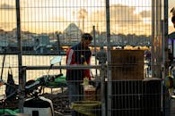 在城市和日落的背景下，一个供应商正在河边附近工作