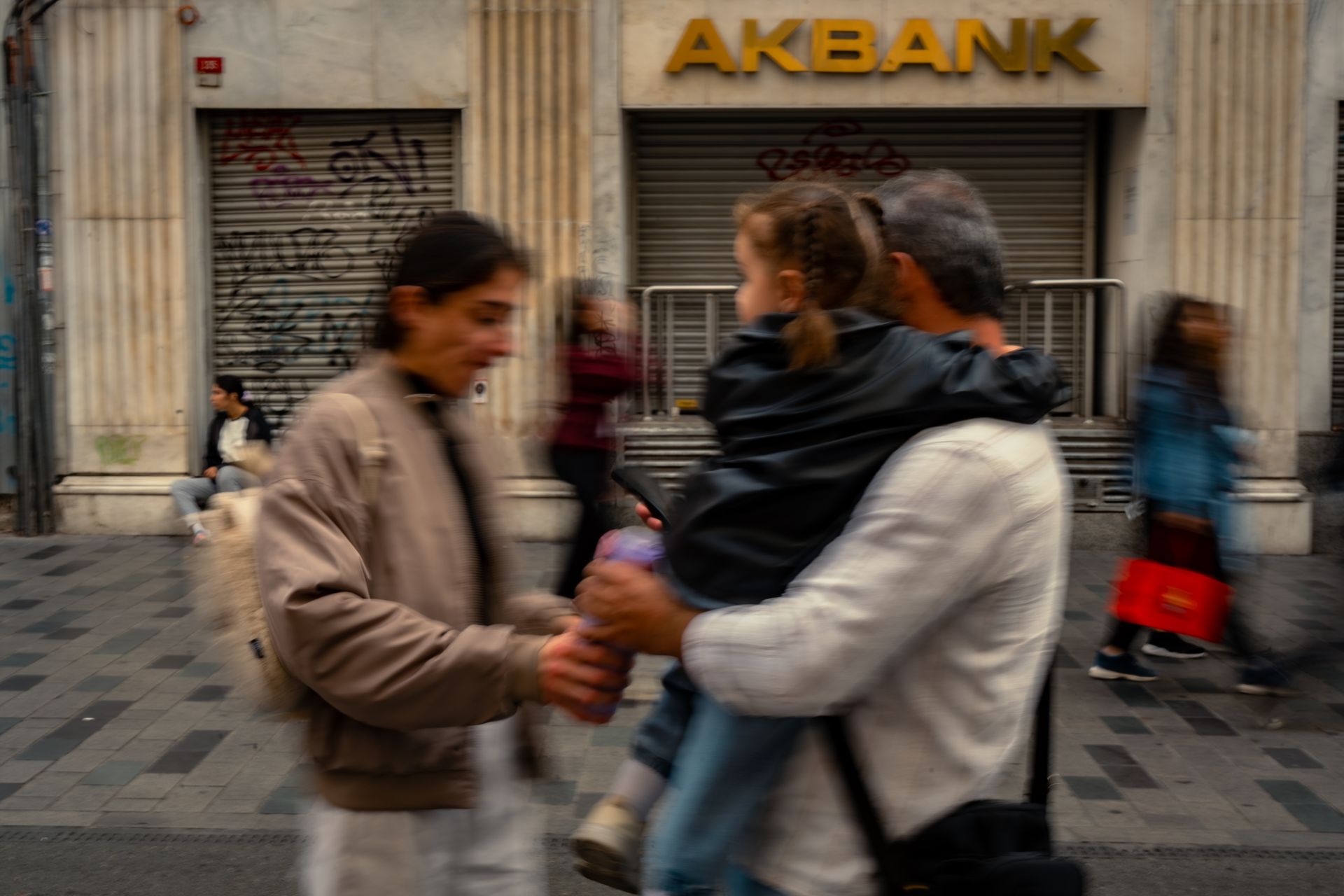 Street scene in front of Akbank showcasing urban life with motion blur.