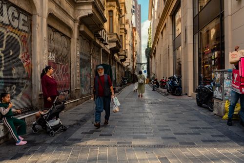 Free A bustling urban alleyway with diverse pedestrians in a historic city street. Stock Photo