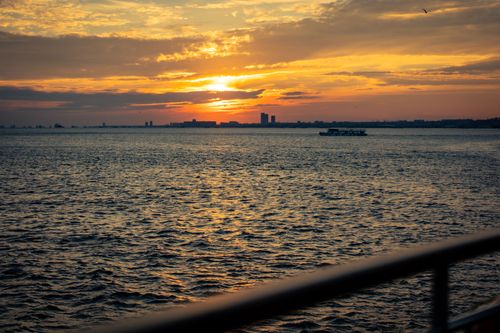 Free Beautiful sunset over a calm sea with distant city skyline and vibrant sky. Stock Photo
