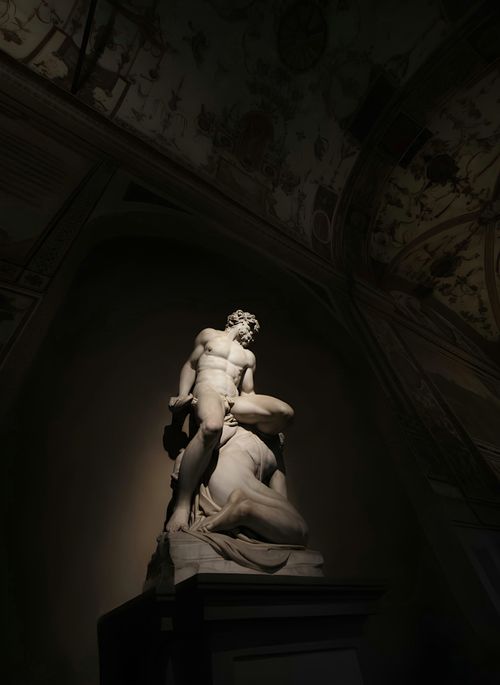 Free Marble sculpture illuminated by dramatic lighting in an indoor museum setting. Stock Photo