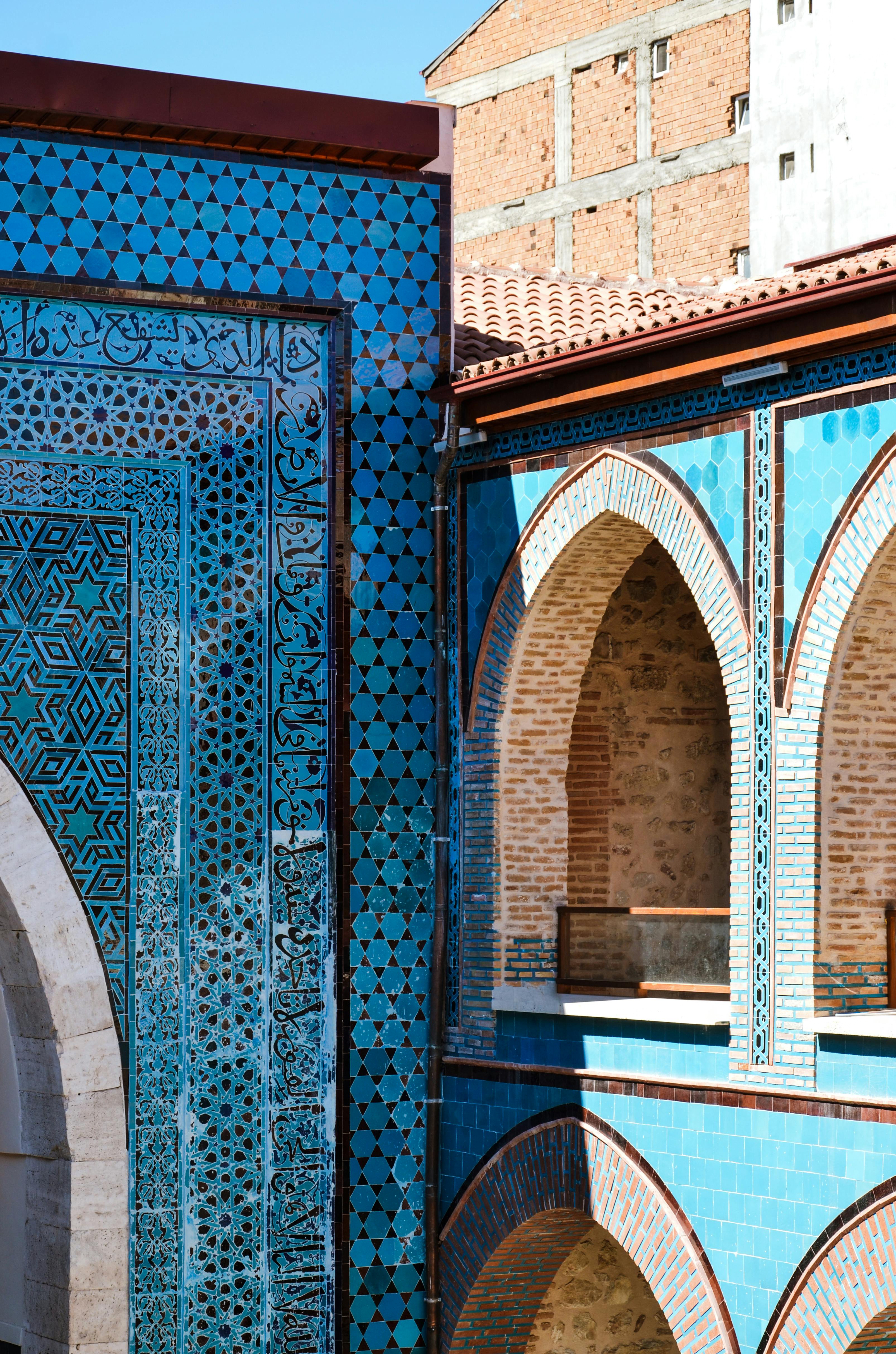 Stunning Seljuk architecture featuring turquoise tile patterns and intricate stonework in a bright courtyard.