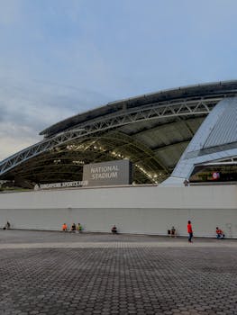 黄昏时，新加坡国家体育场的外部视野广阔，前景中几个人正在拍摄