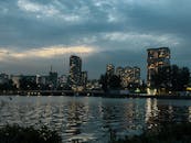 黄昏时，城市天际线在多云的天空下，反射着平静水面上的灯光