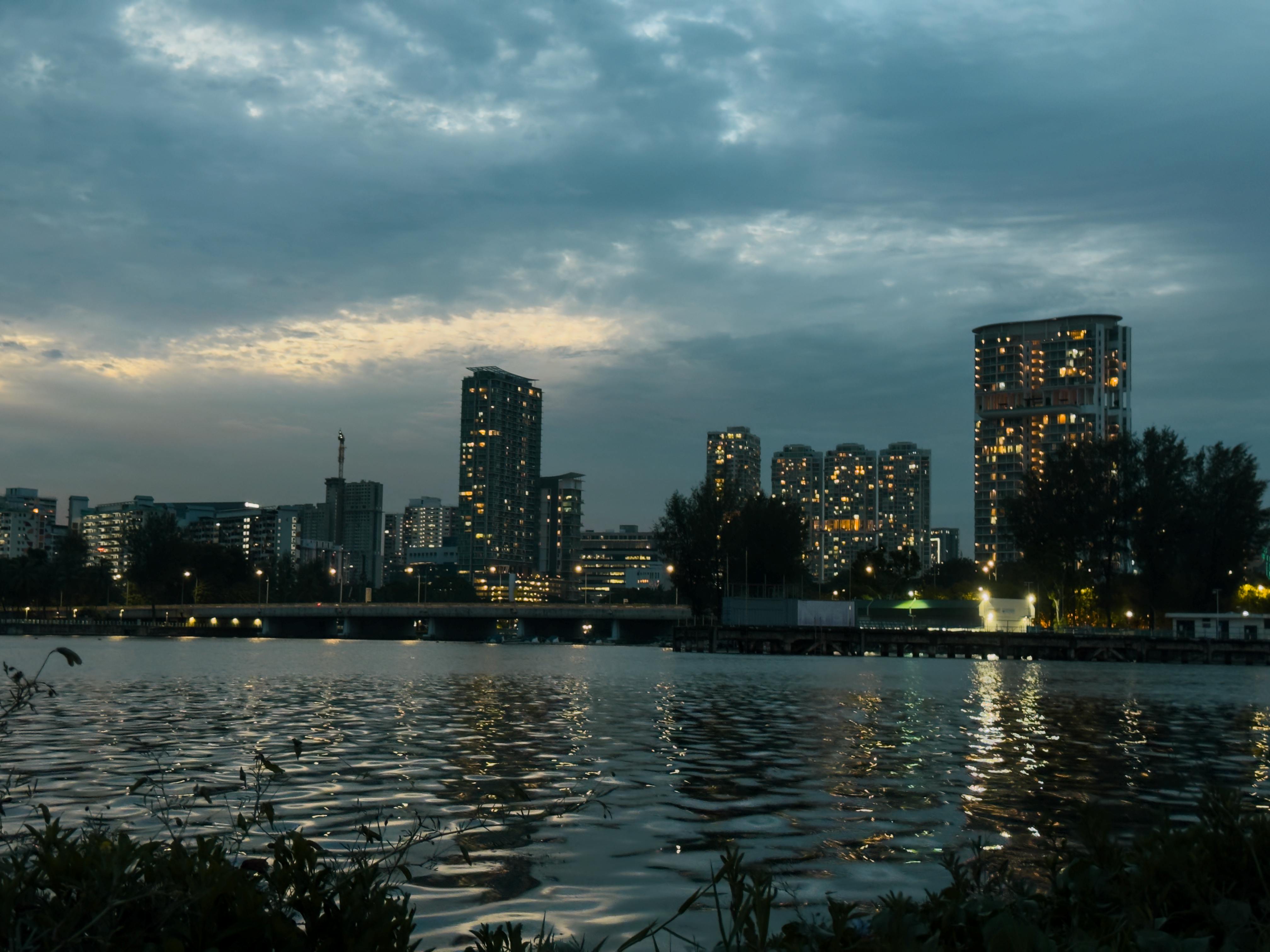 在黄昏时，城市天际线映照在河水上，与照明的建筑物交相辉映