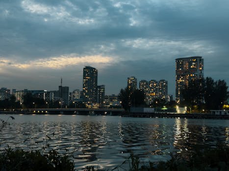 在黄昏时，城市天际线映照在河水上，与照明的建筑物交相辉映