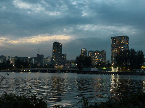 Free City skyline reflected in river water during twilight, with illuminated buildings. Stock Photo