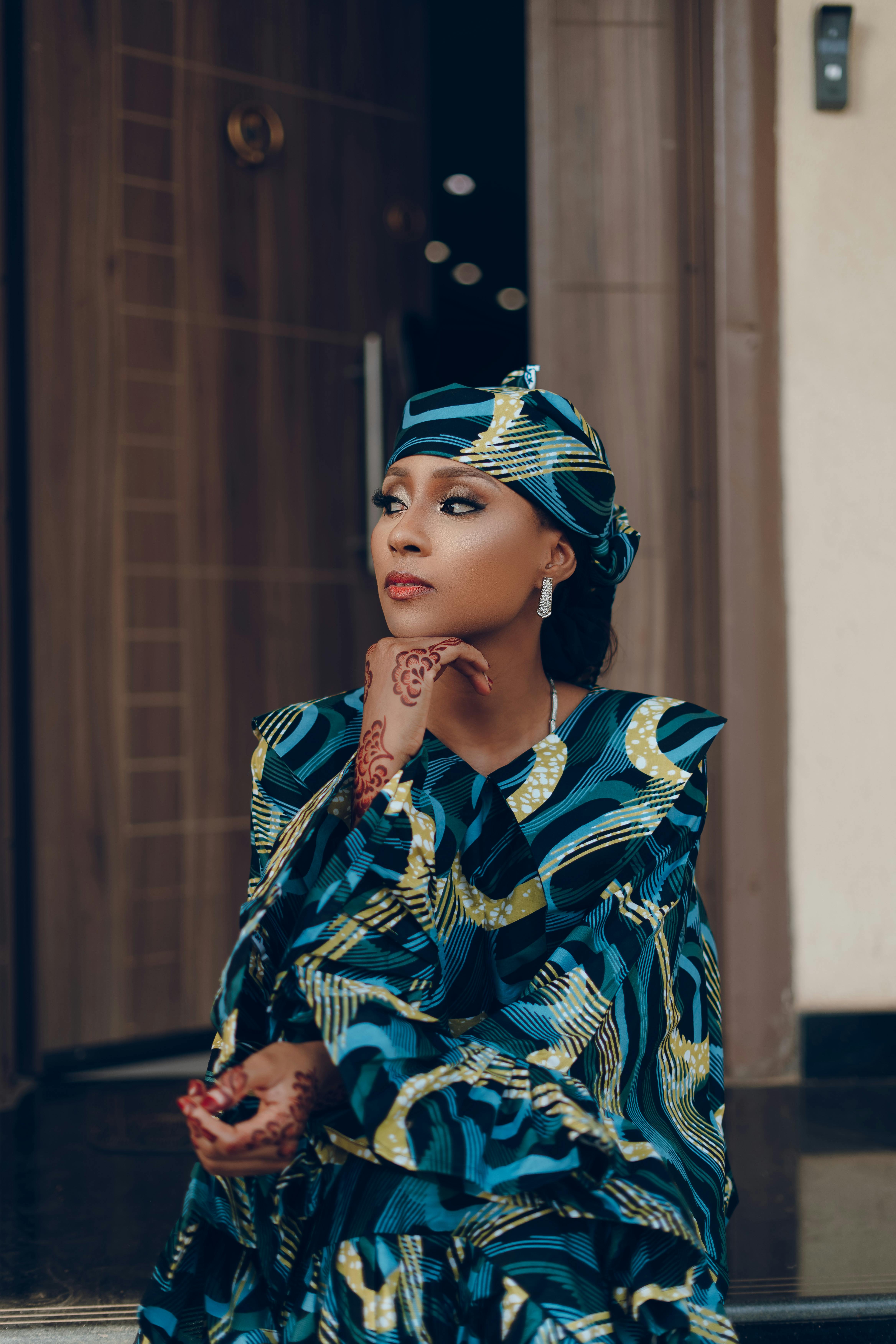 女人穿着充满活力的传统非洲服装，带着指甲花，摆出深思熟虑的姿势