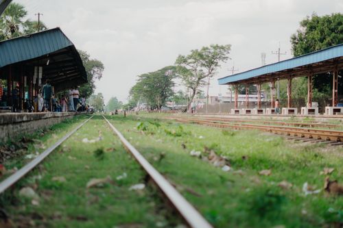 Free A tranquil rural train station with green surroundings and empty tracks. Stock Photo