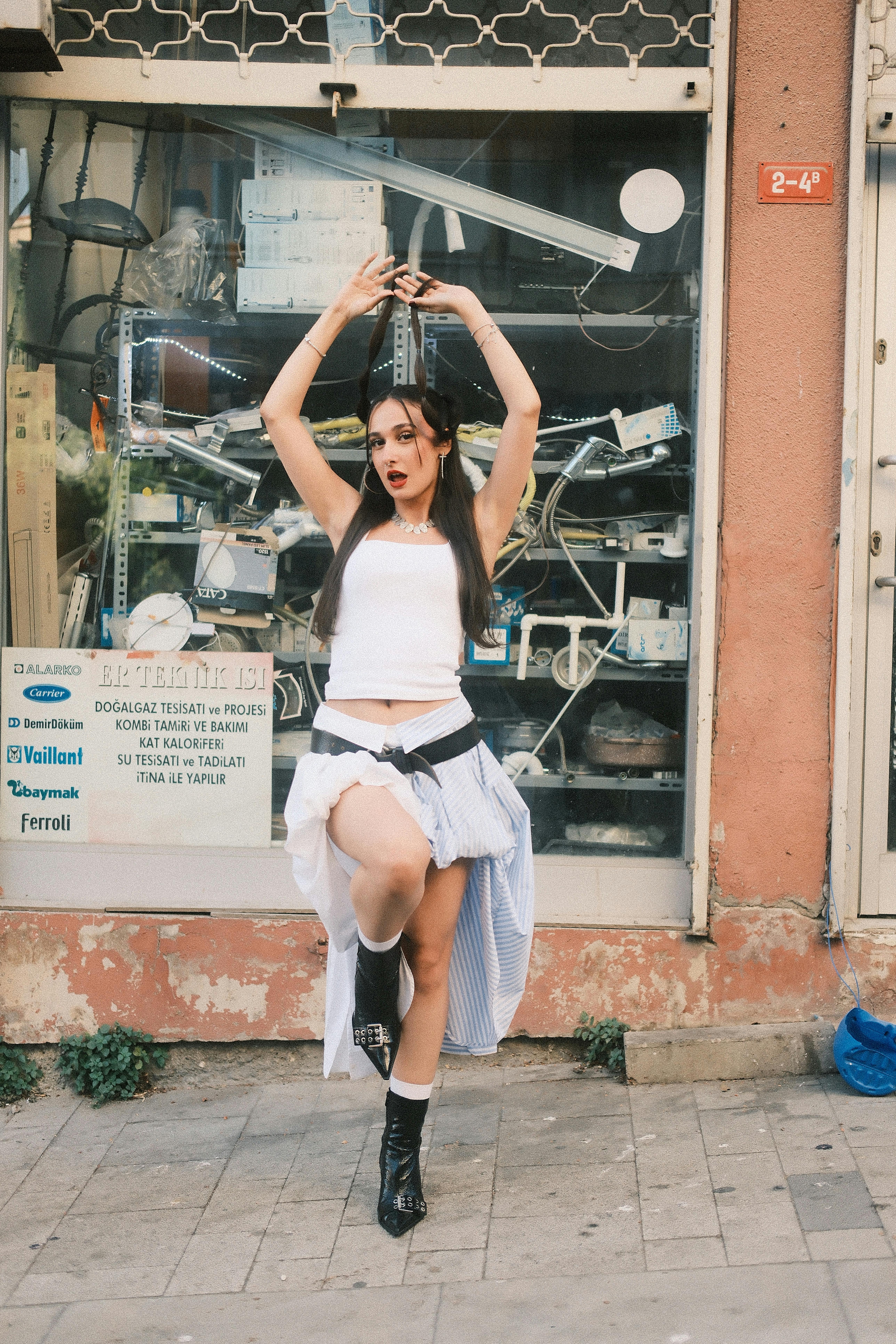 Young woman posing in urban street, dancing with energetic expression.