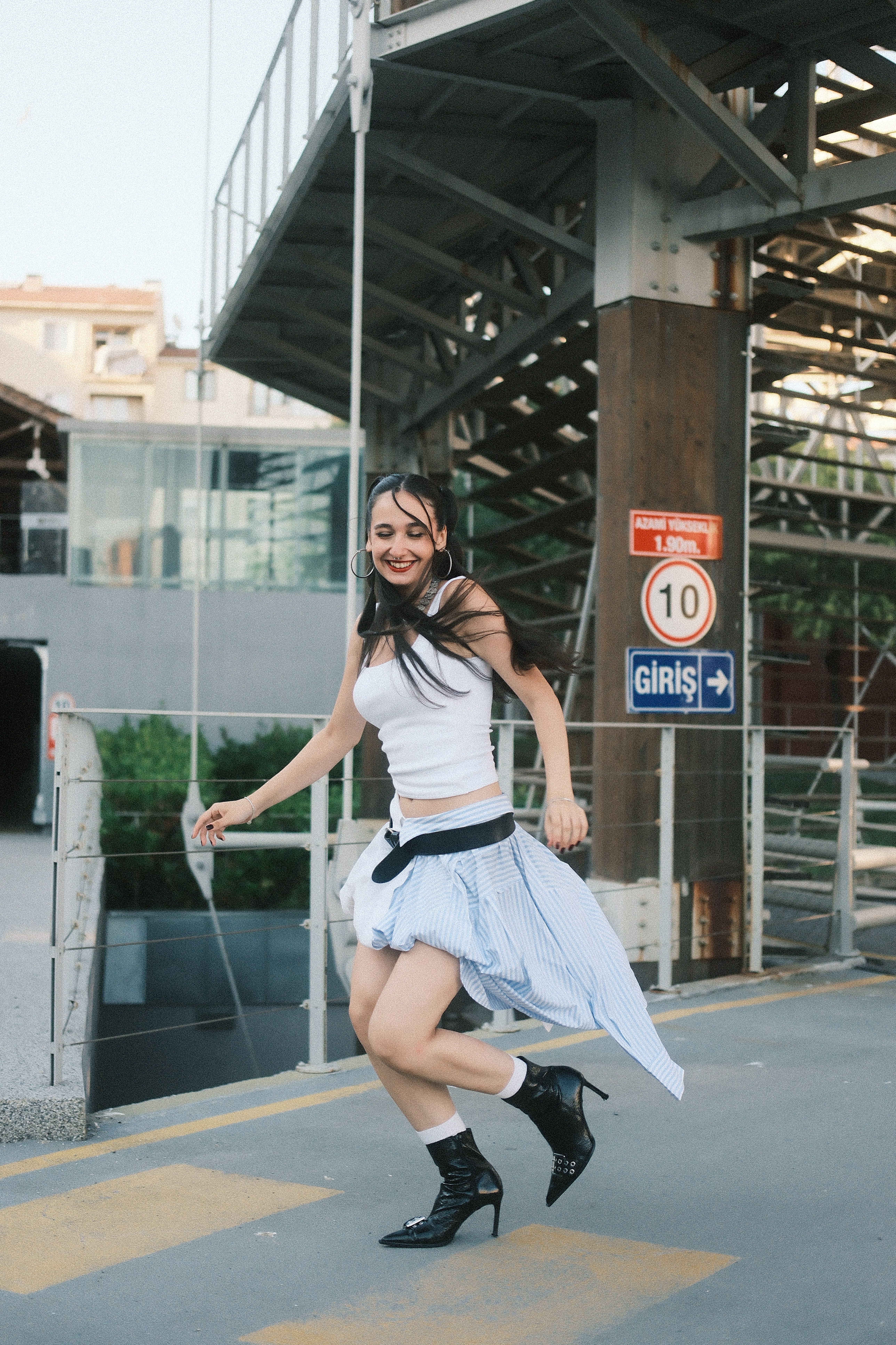 Playful young woman dancing outdoors in an urban setting, expressing happiness and freedom.