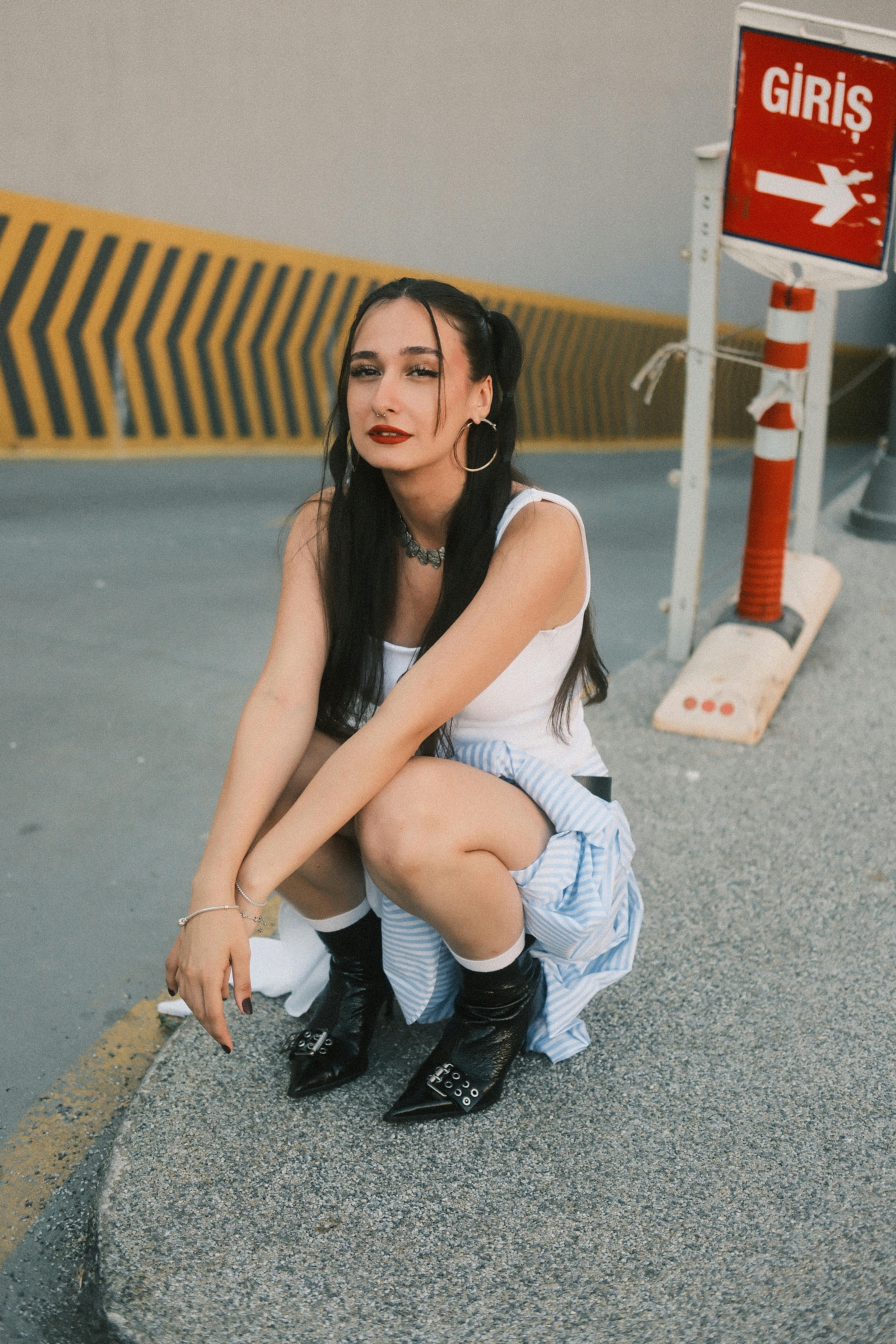 Young woman in trendy outfit poses stylishly in city setting.