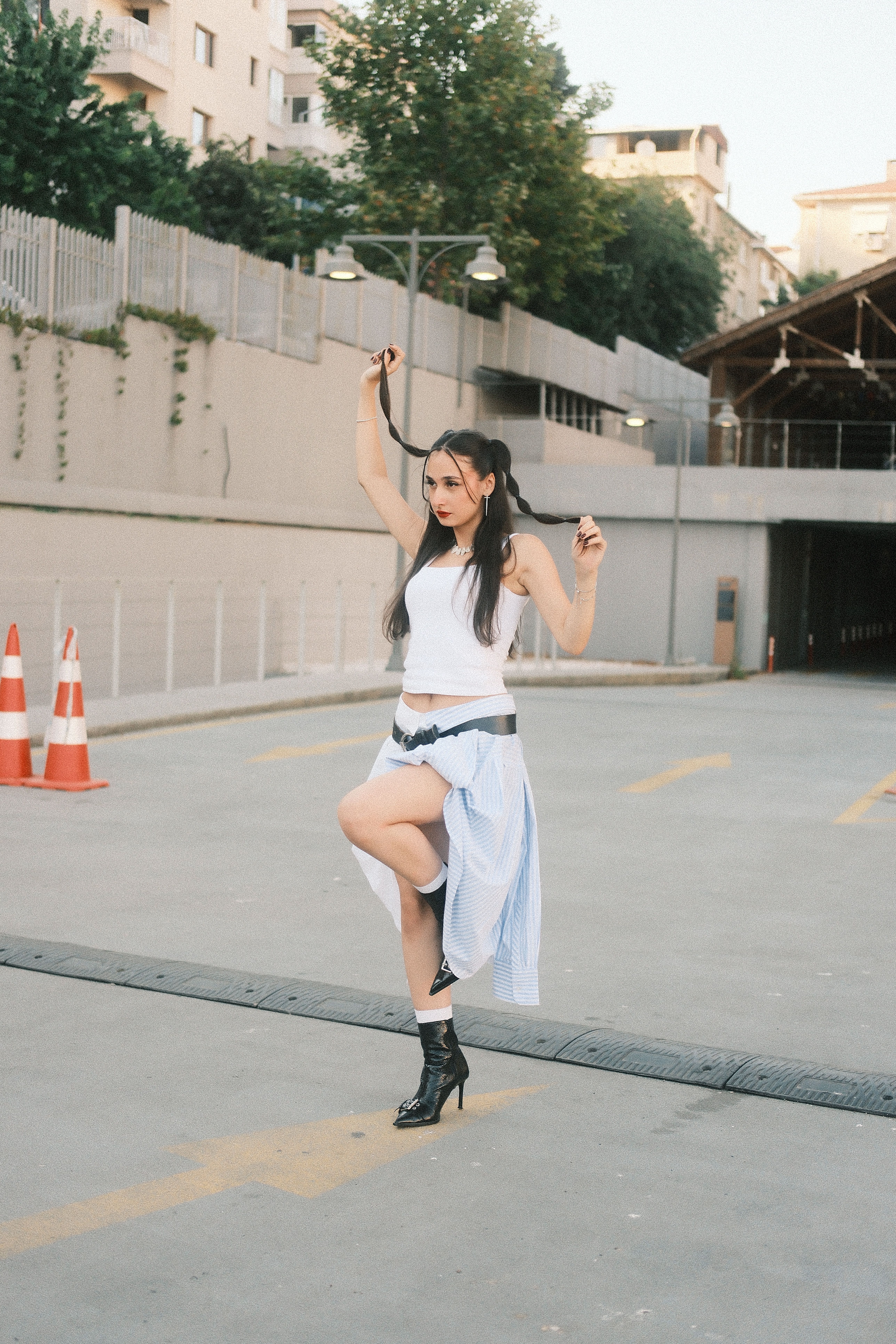 Stylish woman in urban setting, posing creatively with playful attitude.