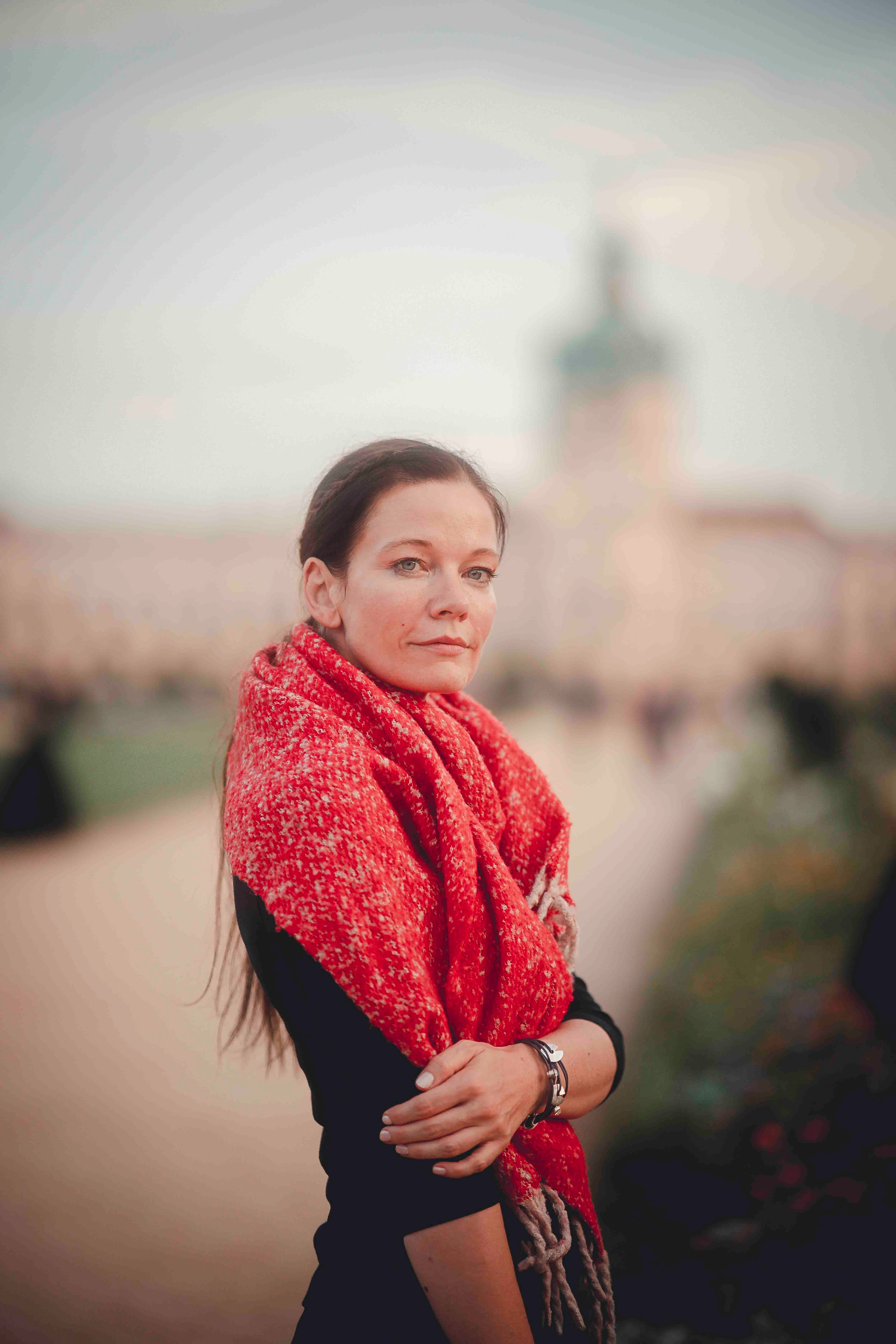 Portrait of a woman in a red scarf at Charlottenburg Palace in Berlin during fall.