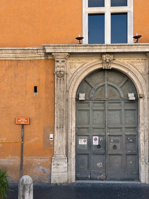 Free Old architectural doorway against a vibrant orange wall with a sign in European street. Stock Photo