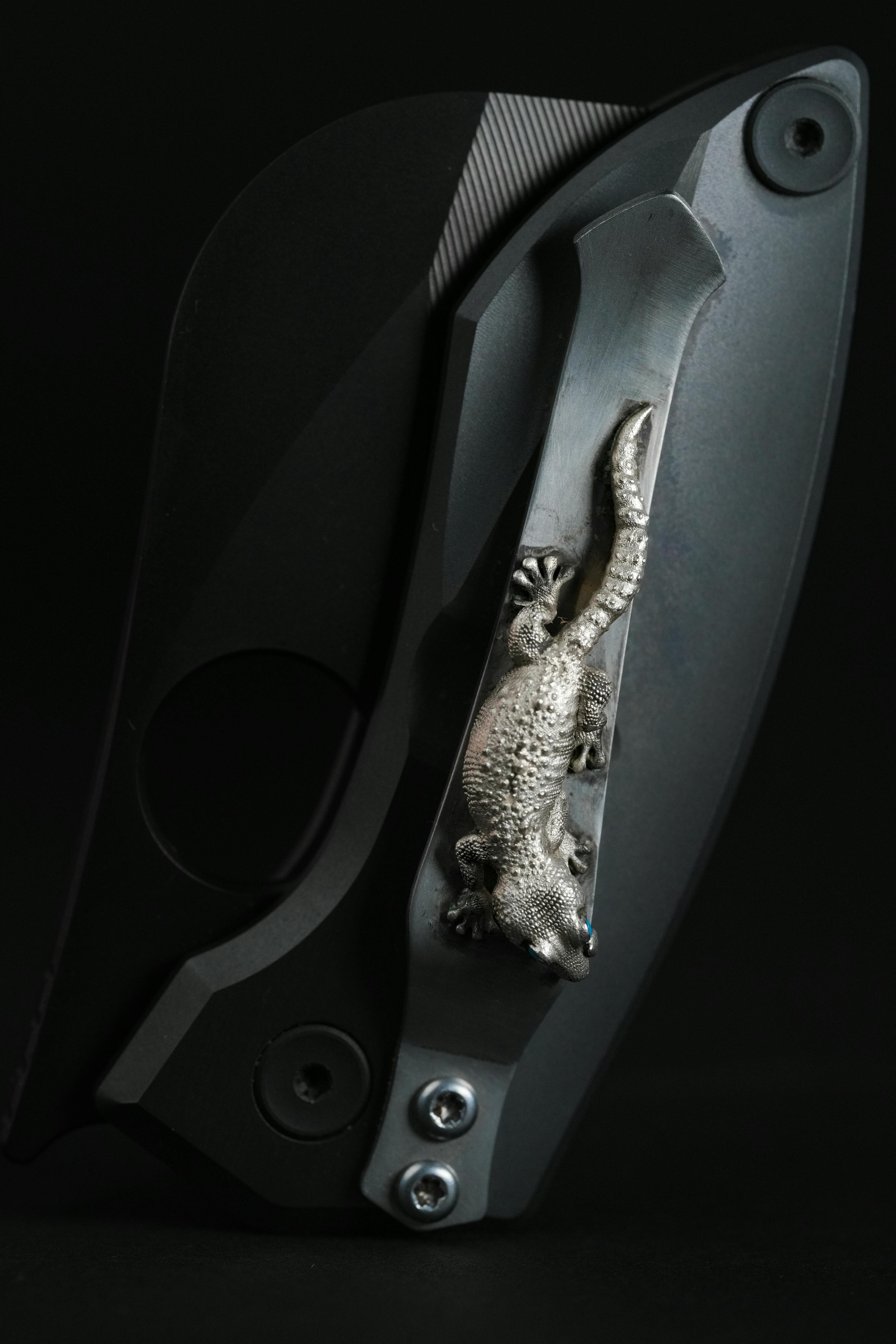Black folding knife featuring detailed silver gecko ornament for a stylish, modern look.