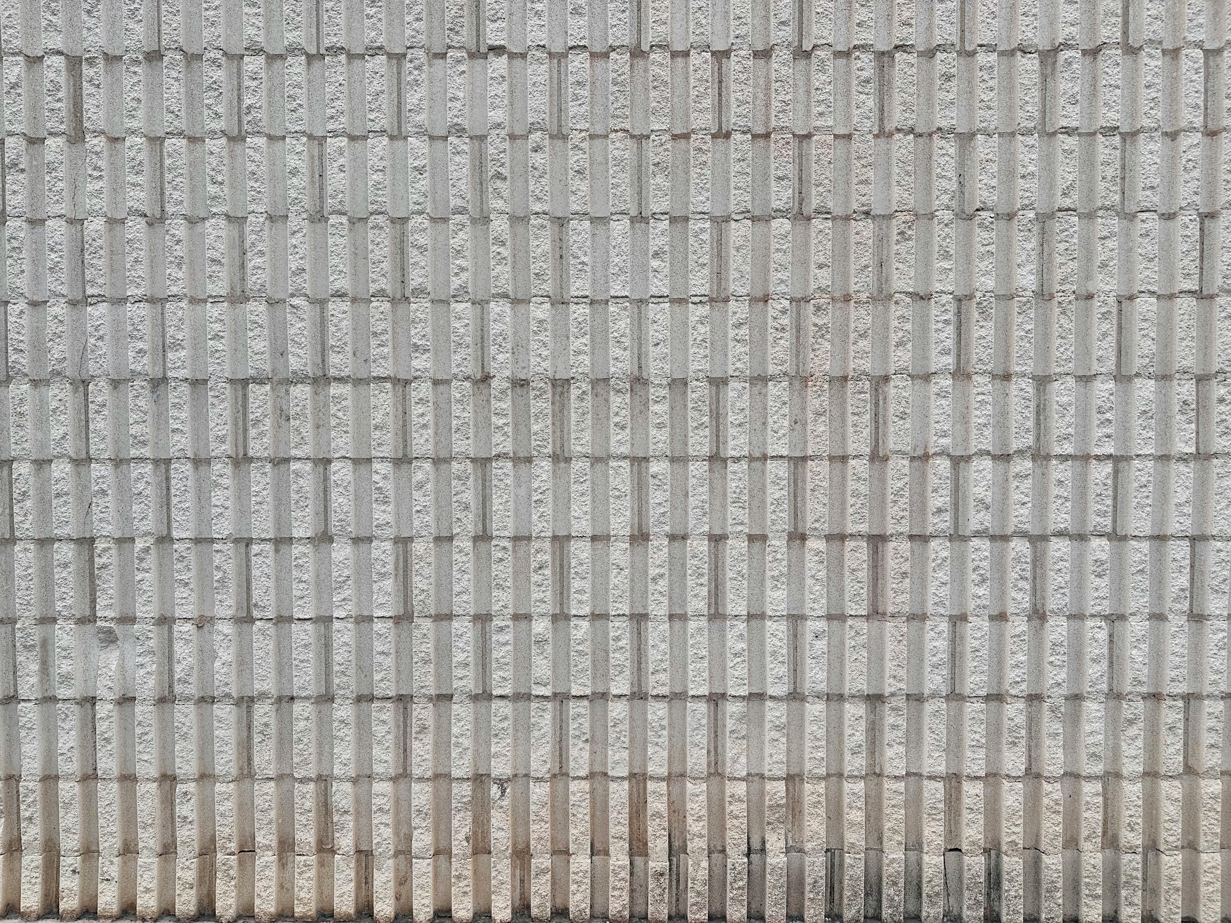 bezplatná Detailní pohled na texturovanou šedou cihlovou zeď, ideální pro pozadí a designové projekty. Základová fotografie