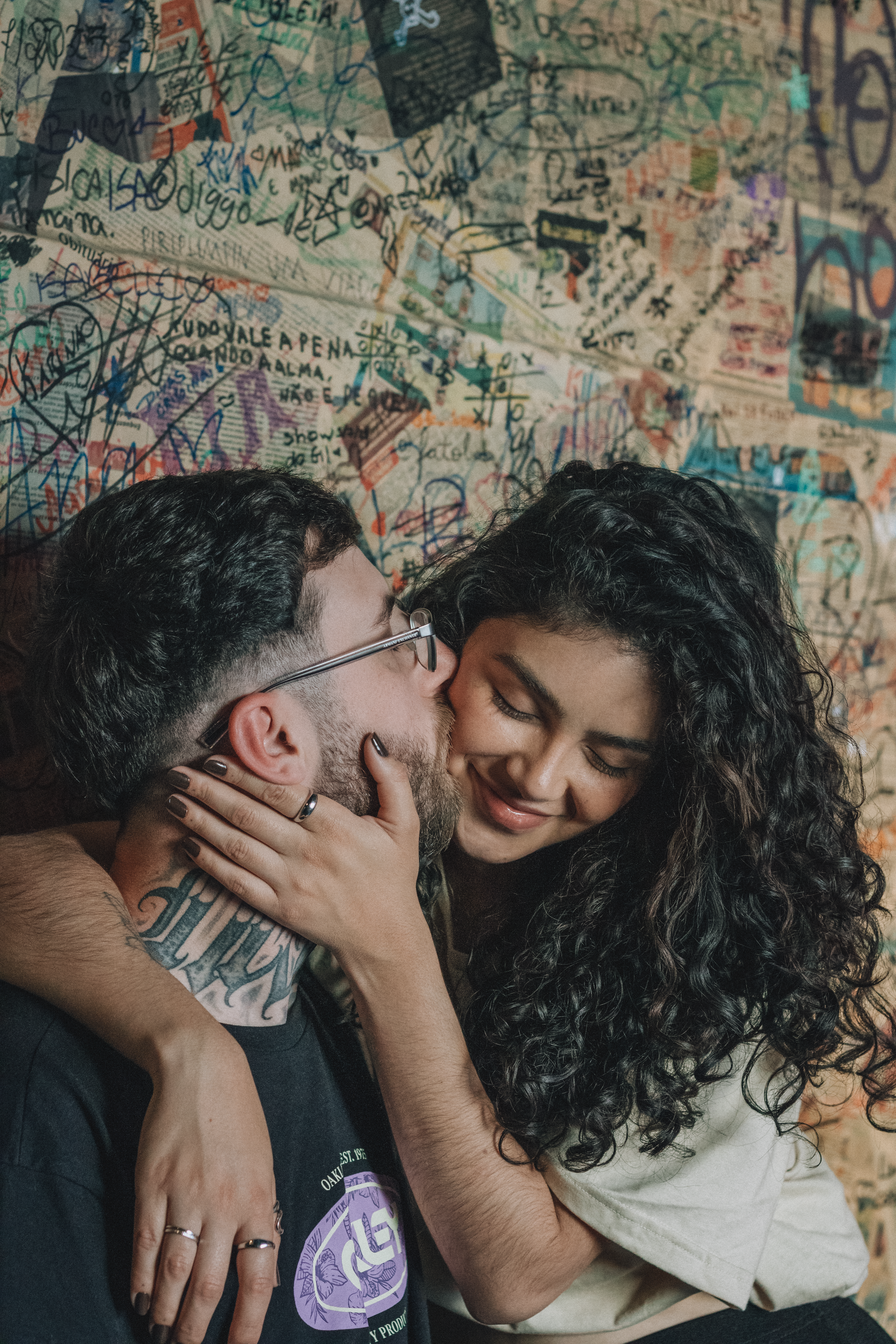 Couple sharing an intimate moment against a colorful graffiti wall.