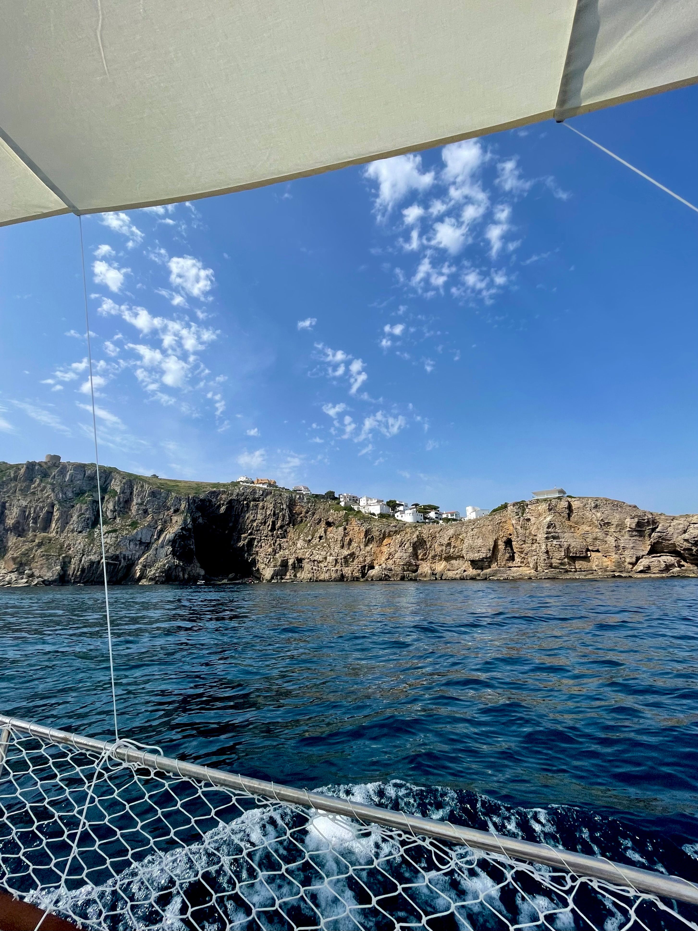 Scenic view of rocky cliffs along the Mediterranean Sea from a sailing boat in L'Escala, Spain.