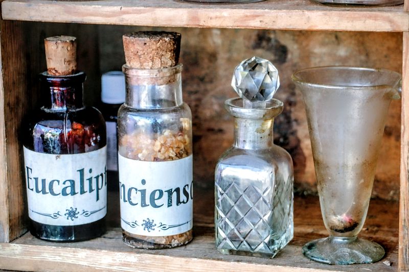 A collection of vintage apothecary bottles on a rustic wooden shelf, perfect for historical or medicinal themes.