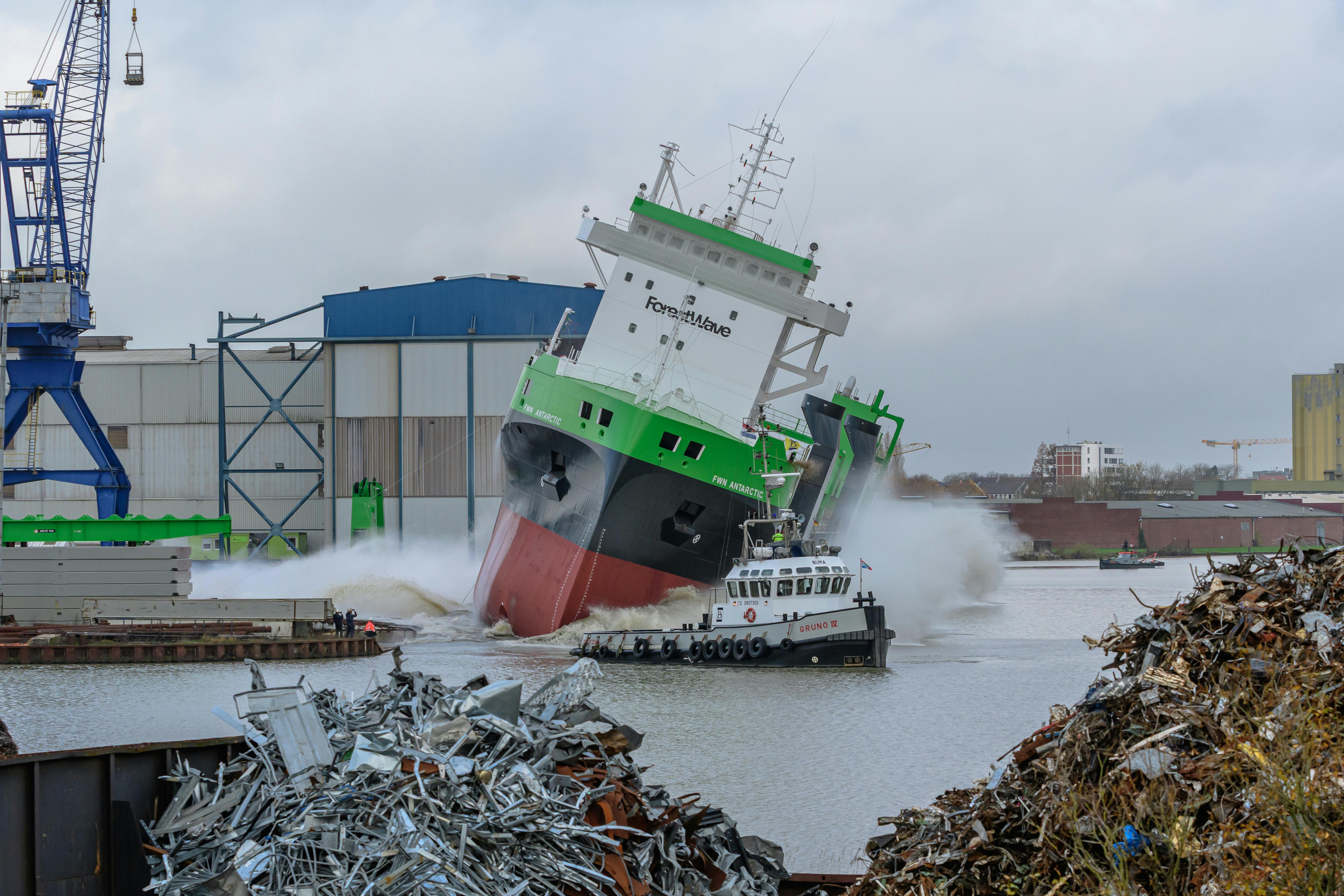 Dramatic ship launch in Niedersachsen shipyard with industrial background.