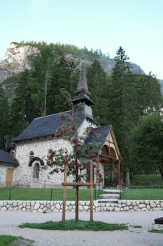 宁静的石头教堂坐落在郁郁葱葱的绿色植物和红色浆果点缀的山脚下