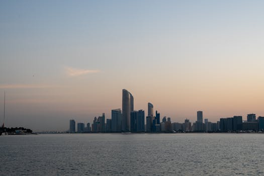 Stunning view of Abu Dhabi's modern skyline at sunrise with a calm sea foreground.