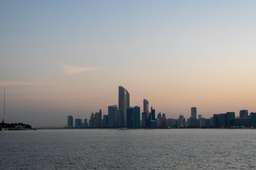 Free Stunning view of Abu Dhabi's modern skyline at sunrise with a calm sea foreground. Stock Photo