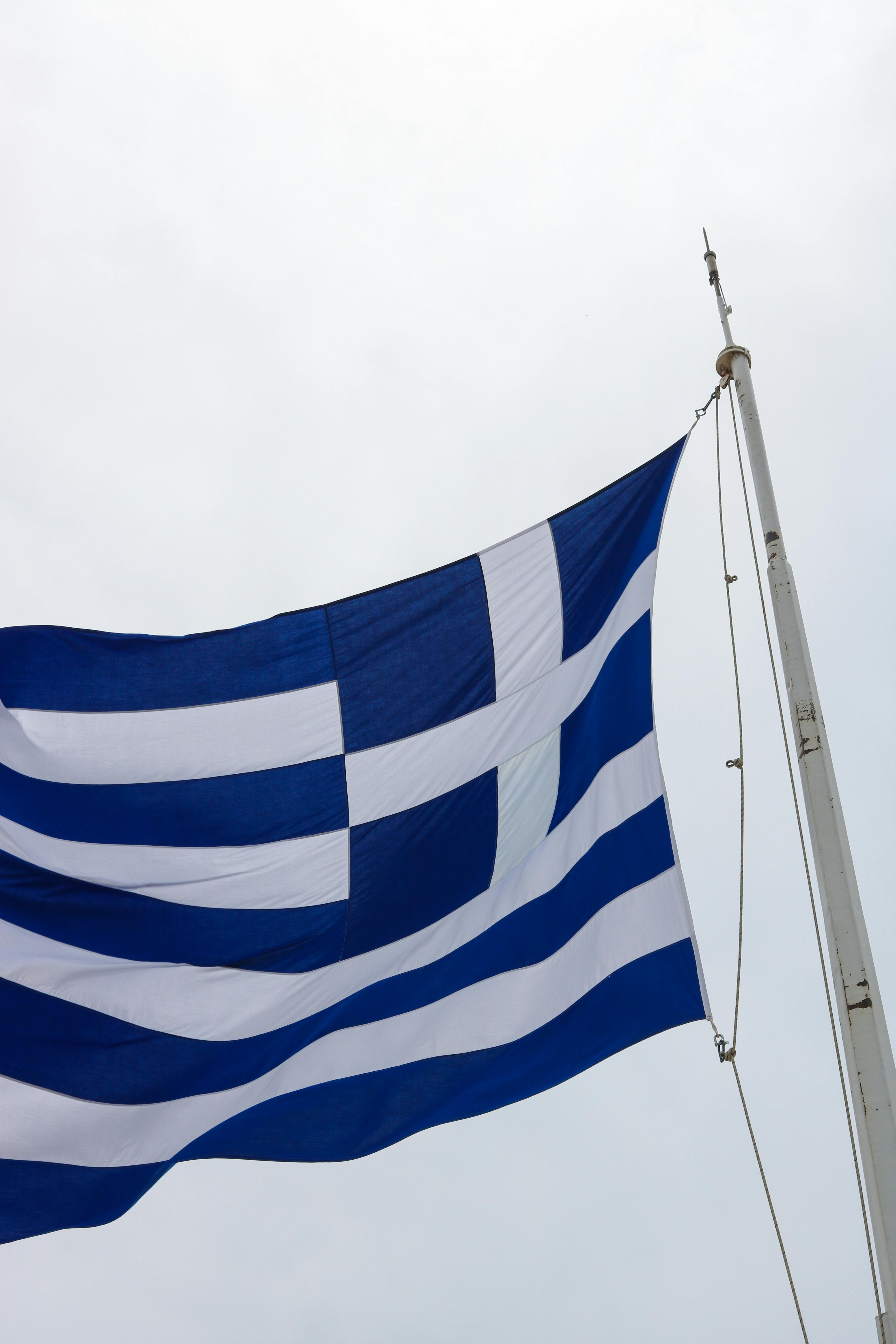 希腊国旗在旗杆上醒目地展示，以抗议晴朗的天空