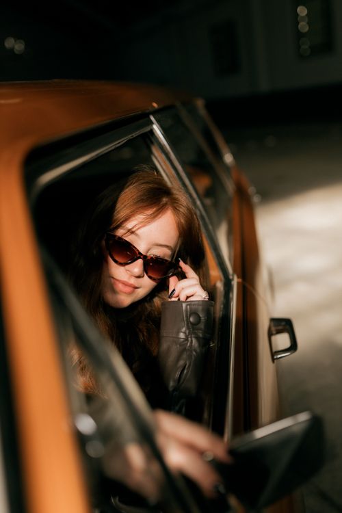 Free Stylish woman in sunglasses sits confidently in a vintage car. Stock Photo