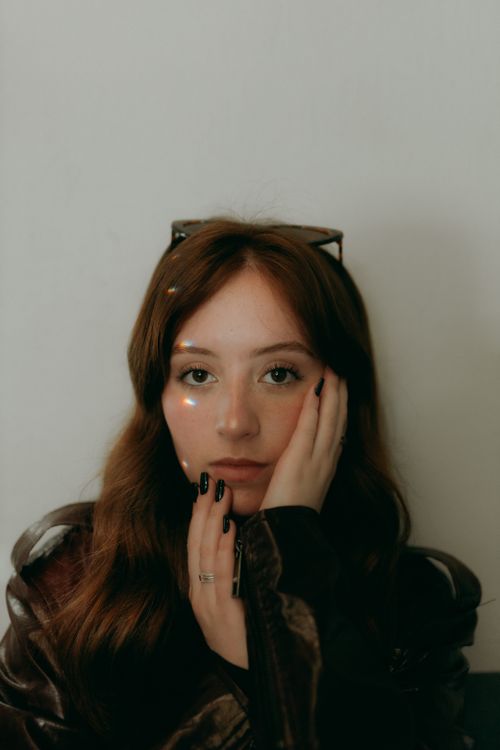 Free Close-up of a young woman with a thoughtful expression and artistic lighting effect. Stock Photo