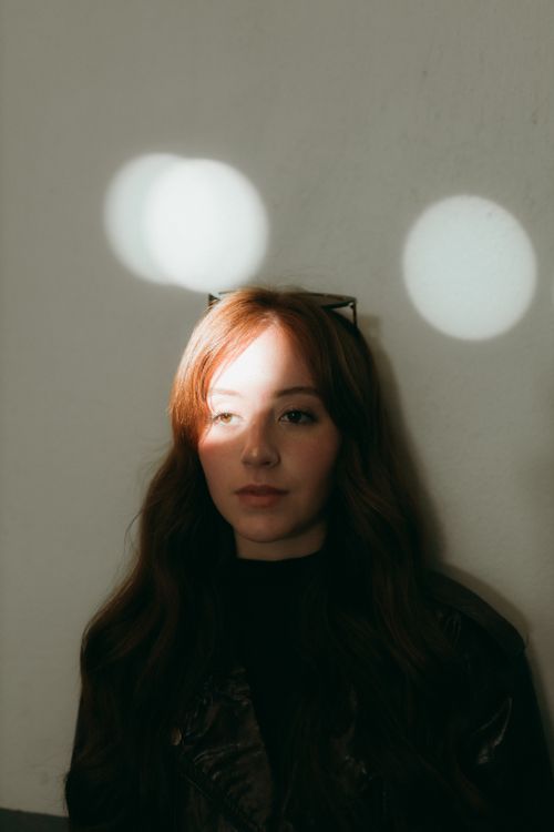 Free Young woman in artistic portrait with light creating playful patterns on wall. Stock Photo