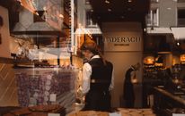 View through a shop window of Läderach store in Switzerland, showcasing employees working.