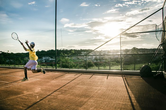 Tennis player serving at golden hour