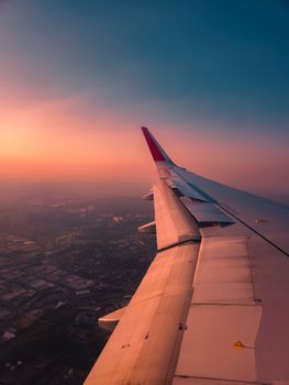 Stunning aerial view of São Paulo, Brazil, showcasing a plane wing against a vibrant sunset.