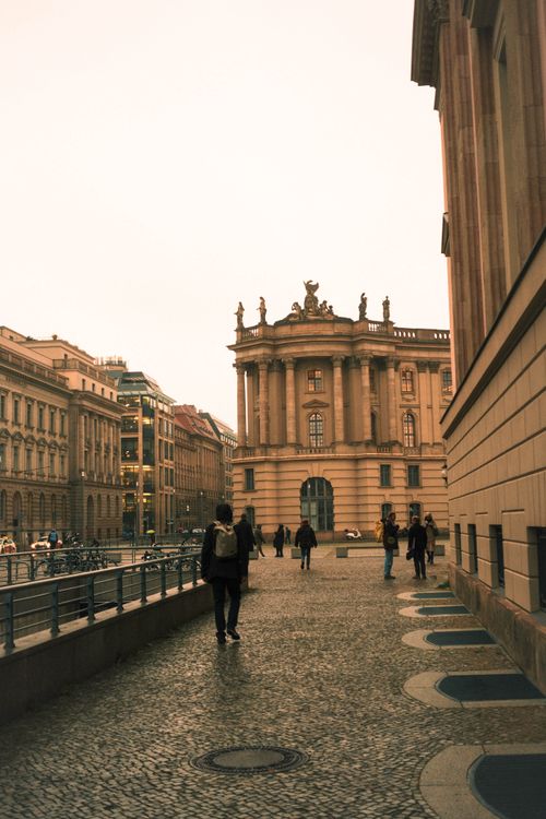 Free People walking by historical buildings in Berlin, Germany, under a cloudy sky. Stock Photo