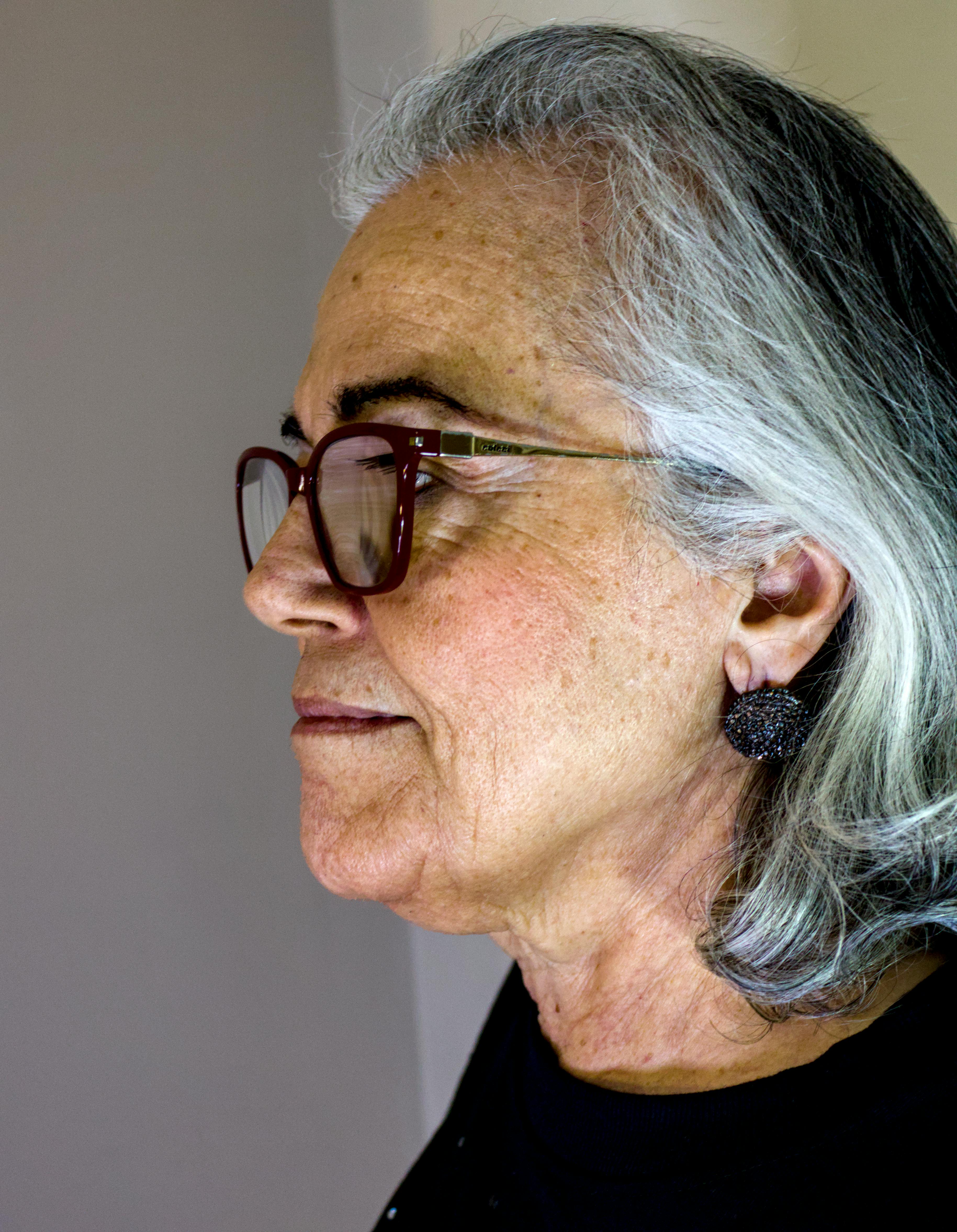 Close-up profile portrait of an elderly woman with glasses, captured indoors in São Paulo.
